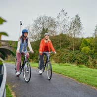 Two people cycling on a greenway