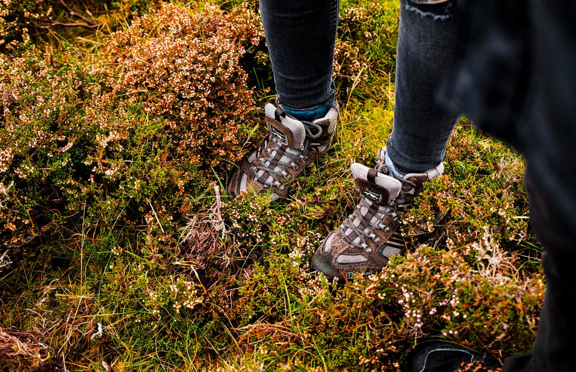 Brown boots in moss on a hiking trail