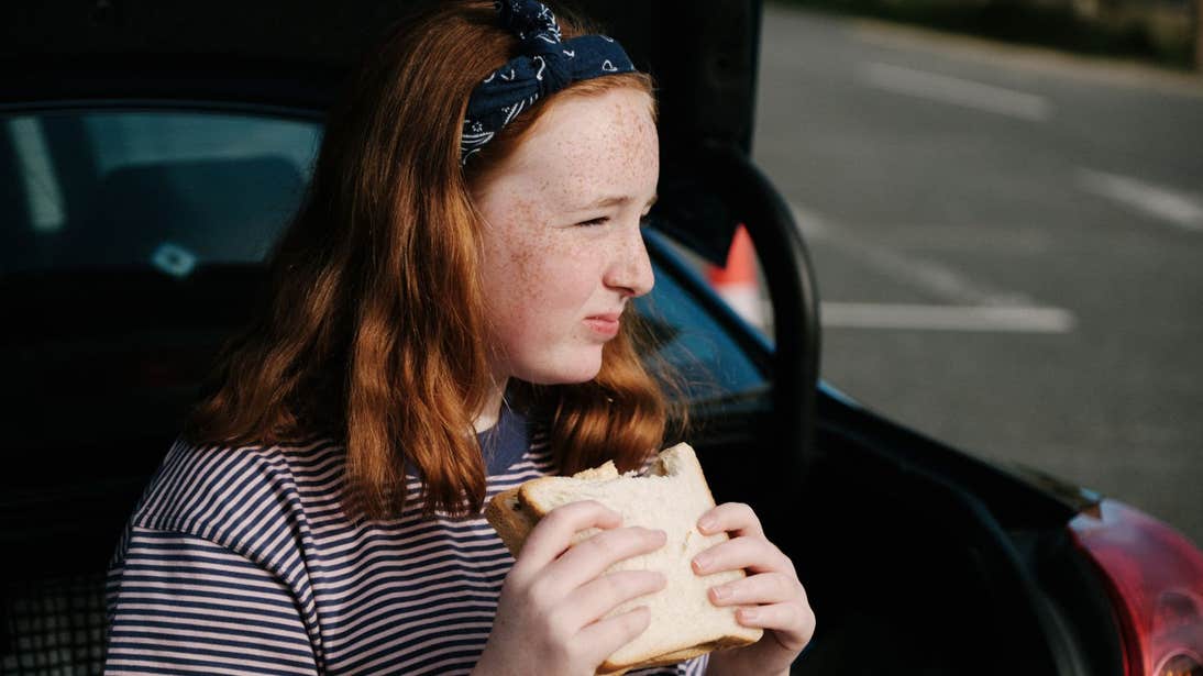 Girl eating a crisp sandwich in the back of the car