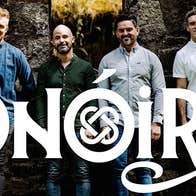 Contemporary Irish folk group Onóir, group of 4 smiling men standing in front of dark stone wall.