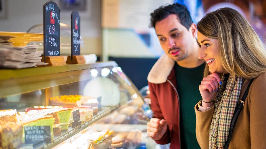 A couple browsing desserts in a café.