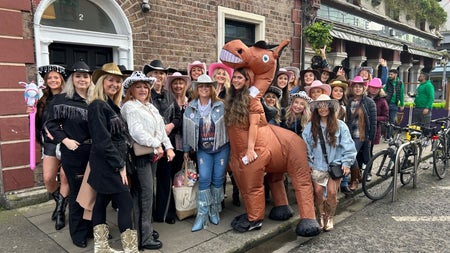 A large group in cowboy themed outfits on a city footpath