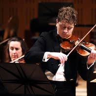 Patrick Rafter playing the violin in concert attire.