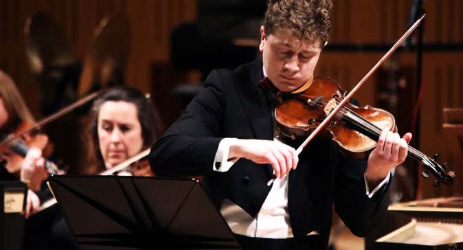 Patrick Rafter playing the violin in concert attire.