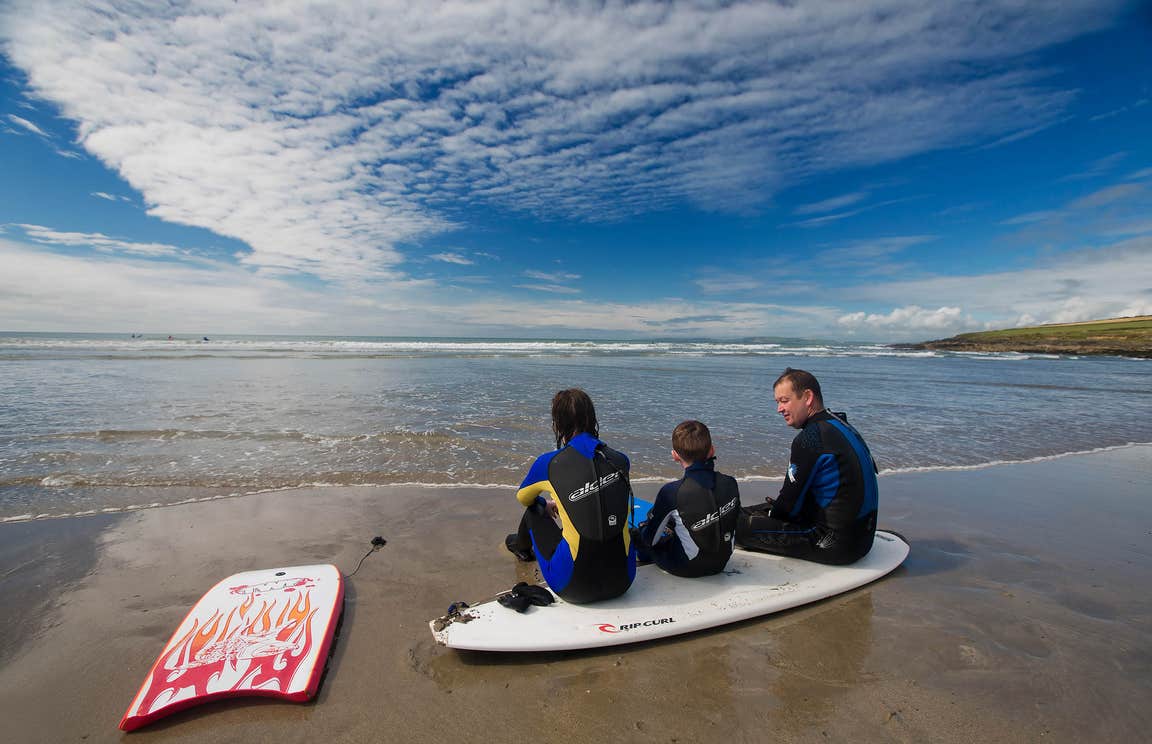 Family at the beach in West Cork with surfboards