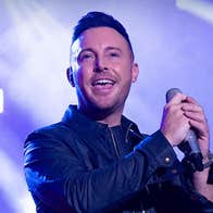 A man singing into mic he is holding.