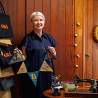 A lady standing in a workshop beside a sewing machine holding linen bunting