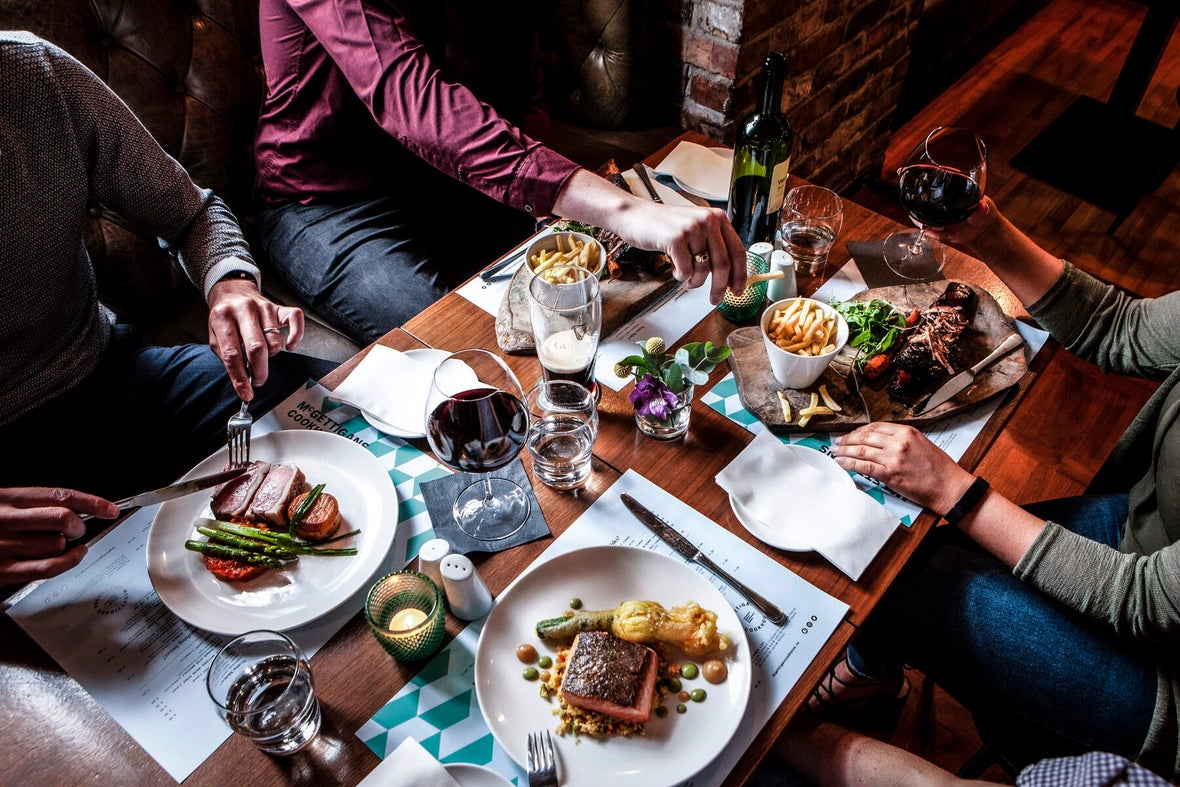 A group of friends sitting around a table of food in The Address Connolly Hotel.