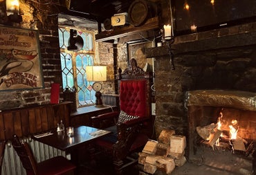 Stone interior of a pub with a lighting wood burning fire and table set for service
