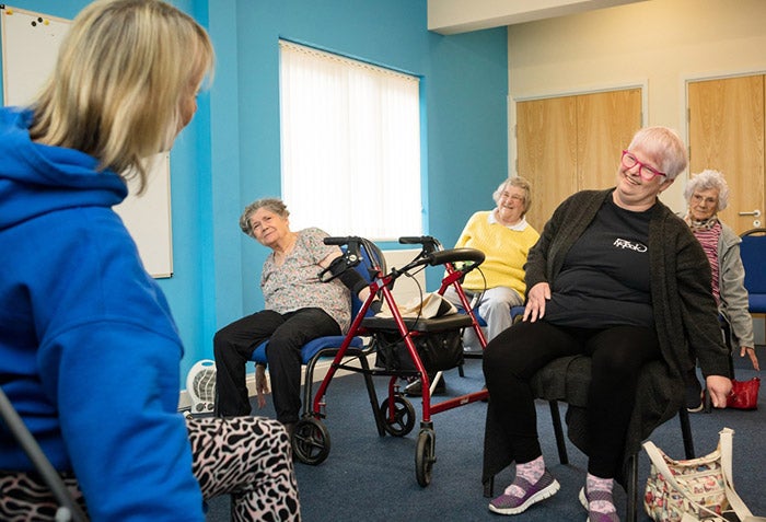 A group of adults doing mobility exercises in chairs