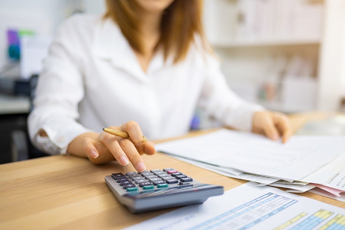 Woman sat at a desk using a calculator 