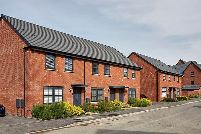 Image showing red brick houses, with leafy green bushes at the front.