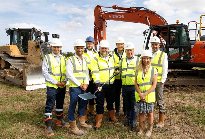 A group of SNG employees wearing hi-vis jackets, posing for the camera on a housing development in Swindon