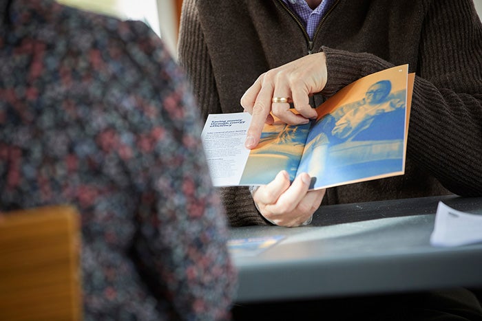 Person showing another person an advice leaflet.