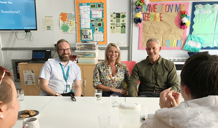 Men and women sitting round a table in a classroom smiling and chatting