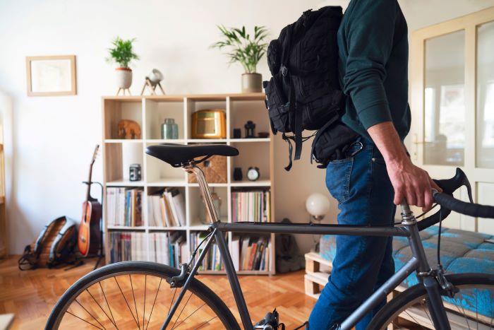 Person wheeling bicycle out from their home